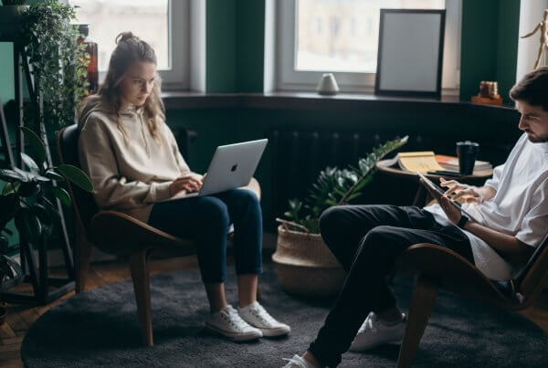 A picture of a man and a woman working on their laptop