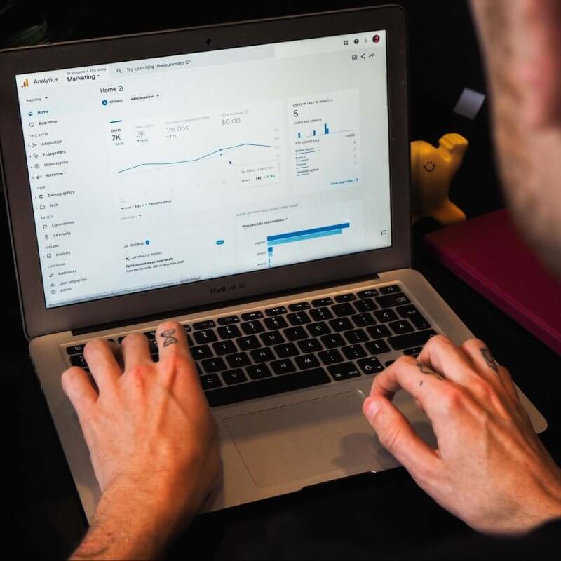 Male typing on a laptop open to data on Google Analytics